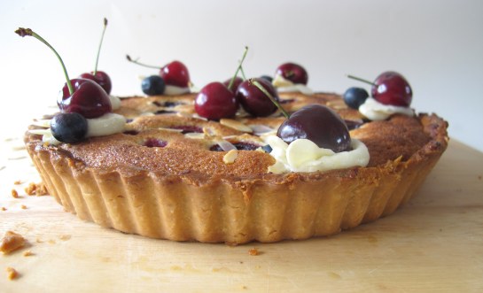 side view of cherry blueberry frangipane tart with almond buttercream